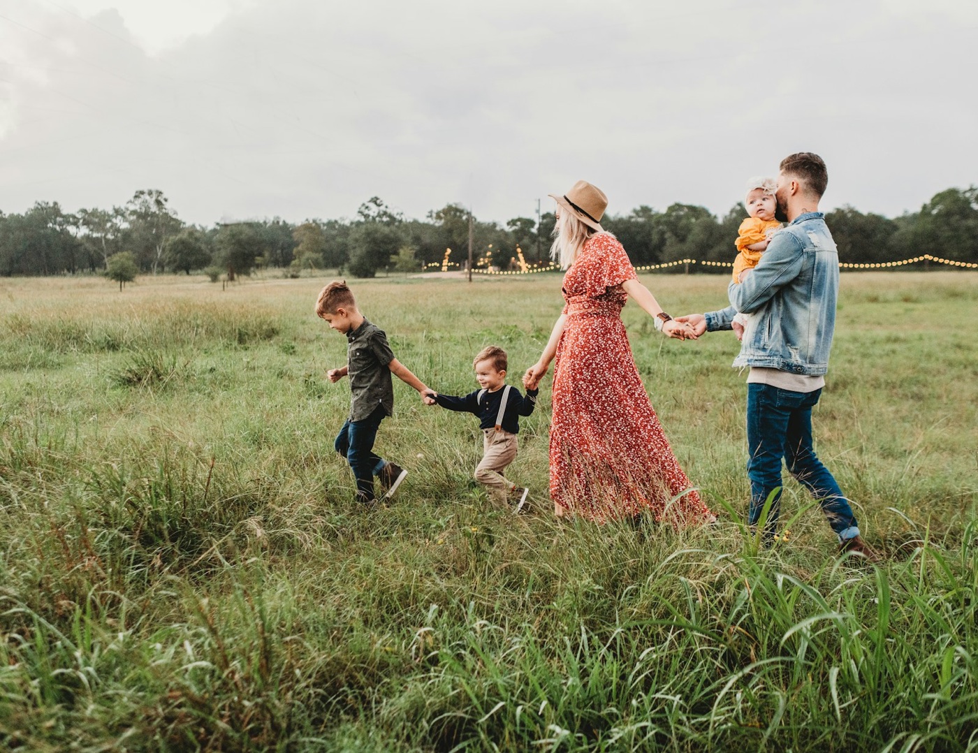Family walking together through a green field, holding hands